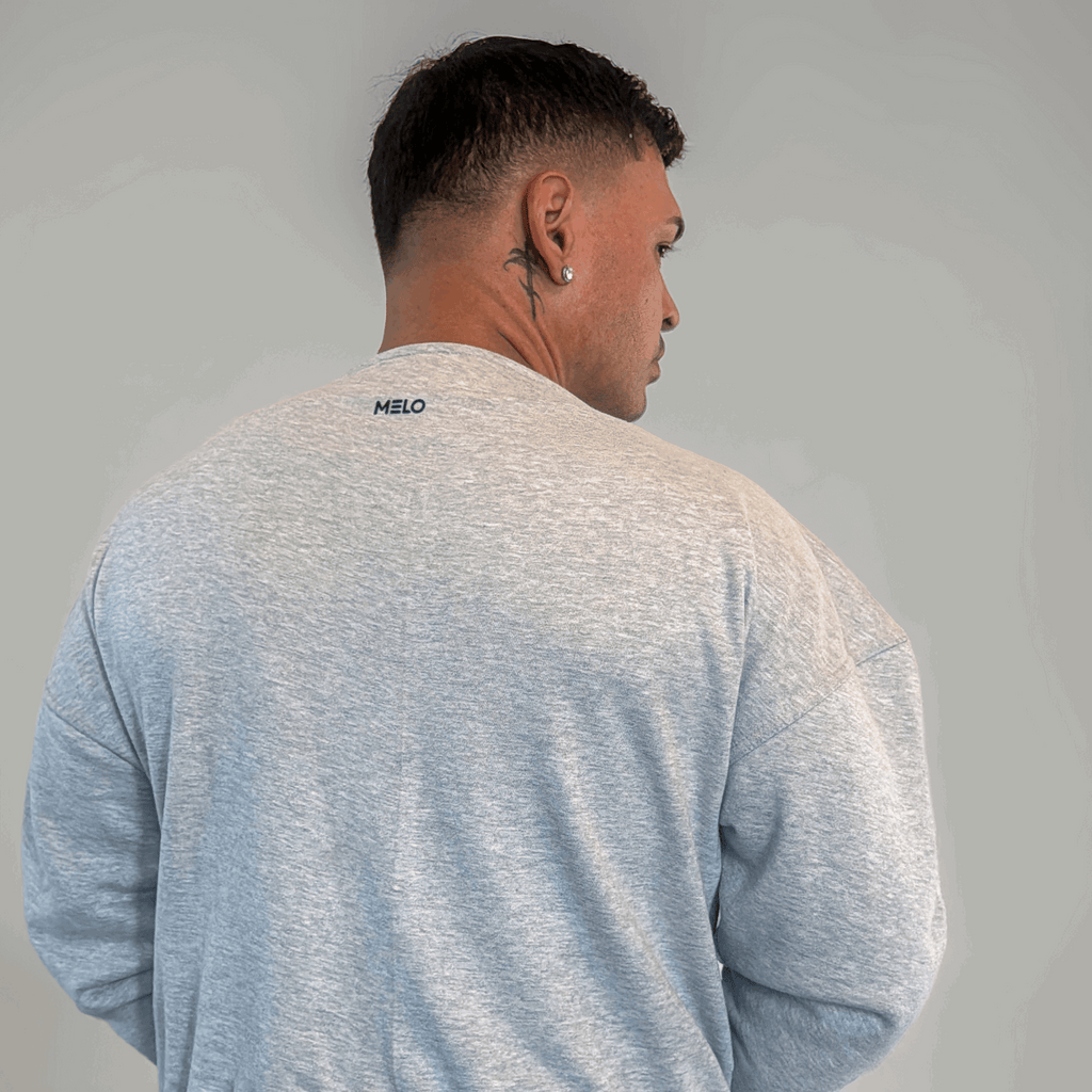 Person wearing a light gray sweatshirt with the word 'MELO' on the back, showcasing a casual style.